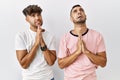 Young gay couple standing over isolated background begging and praying with hands together with hope expression on face very Royalty Free Stock Photo