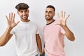 Young gay couple standing over isolated background showing and pointing up with fingers number ten while smiling confident and Royalty Free Stock Photo