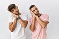 Young gay couple standing over isolated background sleeping tired dreaming and posing with hands together while smiling with Royalty Free Stock Photo