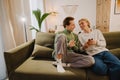 Young gay couple talking and using mobile phone while resting on couch Royalty Free Stock Photo