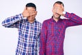 Young gay couple of two men wearing casual clothes covering eyes with hand, looking serious and sad Royalty Free Stock Photo