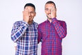 Young gay couple of two men wearing casual clothes covering one eye with hand, confident smile on face and surprise emotion Royalty Free Stock Photo