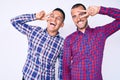 Young gay couple of two men wearing casual clothes doing peace symbol with fingers over face, smiling cheerful showing victory Royalty Free Stock Photo