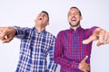 Young gay couple of two men wearing casual clothes laughing at you, pointing finger to the camera with hand over body, shame Royalty Free Stock Photo