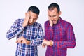 Young gay couple of two men wearing casual clothes looking at the watch time worried, afraid of getting late Royalty Free Stock Photo