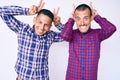 Young gay couple of two men wearing casual clothes posing funny and crazy with fingers on head as bunny ears, smiling cheerful Royalty Free Stock Photo