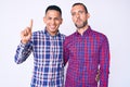 Young gay couple of two men wearing casual clothes showing and pointing up with finger number one while smiling confident and Royalty Free Stock Photo