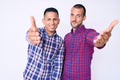 Young gay couple of two men wearing casual clothes smiling cheerful offering palm hand giving assistance and acceptance Royalty Free Stock Photo