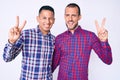 Young gay couple of two men wearing casual clothes smiling with happy face winking at the camera doing victory sign with fingers Royalty Free Stock Photo