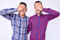 Young gay couple of two men wearing casual clothes smiling and laughing with hand on face covering eyes for surprise Royalty Free Stock Photo