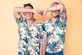 Young gay couple of two men wearing summer hat and hawaiian shirt covering eyes with arm smiling cheerful and funny Royalty Free Stock Photo