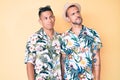 Young gay couple of two men wearing summer hat and hawaiian shirt smiling looking to the side and staring away thinking Royalty Free Stock Photo