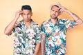 Young gay couple of two men wearing summer hat and hawaiian shirt worried and stressed about a problem with hand on forehead, Royalty Free Stock Photo