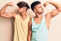 Young gay couple wearing casual clothes showing arms muscles smiling proud