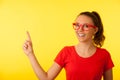 Young geek woman in red t shirt point in copy space over vibrant