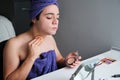 Young gender fluid person applying make-up base after shower.