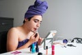 Young gender fluid person man applying lipstick.