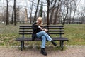 Young generation Z hipster girl sitting in park on a bench with her adopted dog, whom she rescued from the street from starvation