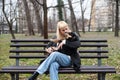 Young generation Z hipster girl sitting in park on a bench with her adopted dog, whom she rescued from the street from starvation Royalty Free Stock Photo