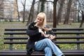 Young generation Z hipster girl sitting in park on a bench with her adopted dog, whom she rescued from the street from starvation Royalty Free Stock Photo