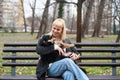 Young generation Z hipster girl sitting in park on a bench with her adopted dog, whom she rescued from the street from starvation Royalty Free Stock Photo