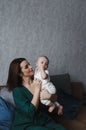 A young gentle happy mother hugs her newborn baby, smiling, sitting at home on the couch. Royalty Free Stock Photo