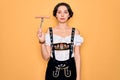 Young german woman with blue eyes wearing octoberfest dress holding fork with sausage with a confident expression on smart face Royalty Free Stock Photo