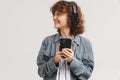 Young ginger joyful woman listening music with headphones and cellphone Royalty Free Stock Photo