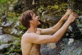 Young ginger man standing by rocks while traveling in nature