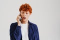 Young ginger man talking on cellphone and expressing surprise Royalty Free Stock Photo
