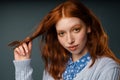 Young ginger woman looking at camera and holding strand of her hair Royalty Free Stock Photo