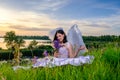 Young girl with angel wings sits on a meadow with wildflowers bouquet
