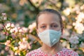 Young girl in an apple orchard with anti-smog mask on the face.