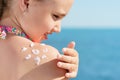 Young girl applyng sun protector cream at her shoulder on the beach close to tropical turquoise sea under blue sky Royalty Free Stock Photo