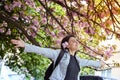 Young girl with arms wide open enjoying sunshine standing on the background of blooming sakura Royalty Free Stock Photo