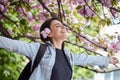 Young girl with arms wide open enjoying sunshine standing on the background of blooming sakura Royalty Free Stock Photo