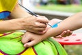 Young girl artist draws drawing on child& x27;s hand. Painting skin with paints Royalty Free Stock Photo