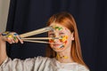 The young girl of the artist in a light white dress, paints a picture on canvas in the workshop. The face is stained with paints. Royalty Free Stock Photo