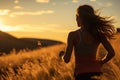 A young girl athlete runs towards the sun in the mountains at sunset