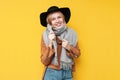 Girl in autumn clothes and a scarf smiles on a yellow isolated background, a woman warmly dressed in autumn