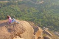 A young girl on a background of sunrise or sunset sits on top of