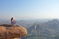 A young girl on a background of sunrise or sunset sits on top of