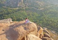 A young girl on a background of sunrise or sunset sits on top of