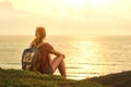 Young girl with backpack enjoying sunset listening to music on p Royalty Free Stock Photo