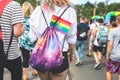 Young girl with a backpack and a rainbow LGBT flag with bisexuality sign. View from the back