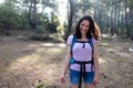 A young girl with a backpack travels through the forest. Tourist hike in the forest and mountains. The girl smiles at the camera