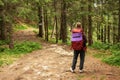 Young girl with backpack trekking forest path for hiking in mountain route