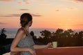 Young girl on balcony with cup of coffee looking at the sea and the sunset Royalty Free Stock Photo