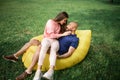 Young girl and balding man relaxing on air hammock in the garden. Spring or summer love story