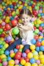 Young girl in ball pit throwing colored balls
